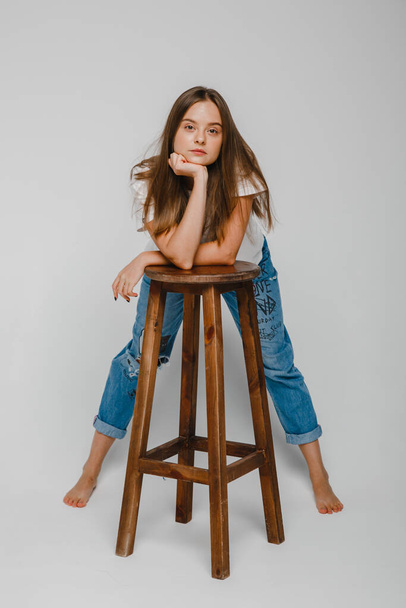 δοκιμές μοντέλου. Όμορφο κορίτσι με μακριά μαλλιά στέκεται κοντά σε καρέκλα και ποζάρουν - Φωτογραφία, εικόνα