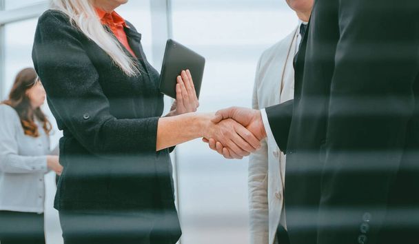 át a redőnyön. sikeres üzleti partnerek találkoznak egymással egy kézfogással - Fotó, kép