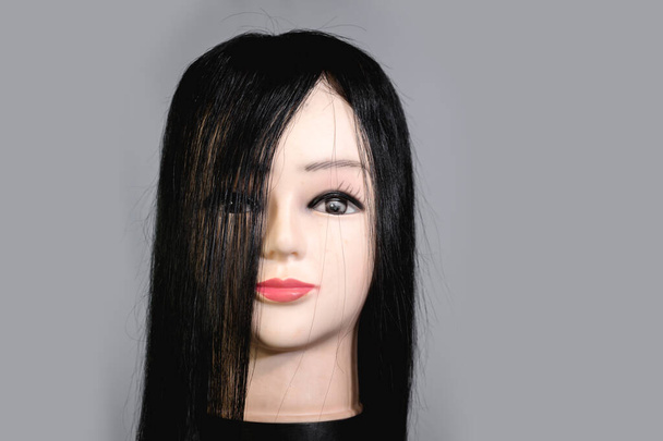 Вид спереди головы манекена в длинном черном парике или тулупе. - Фото, изображение