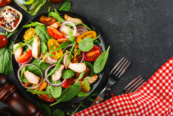 Fresh salad with spinach, chicken, tomatoes, arugula, corn lettuce and onion. Healthy food. Black table - Valokuva, kuva