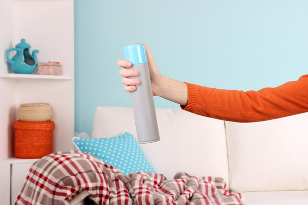 Sprayed air freshener in hand on home interior background - Zdjęcie, obraz