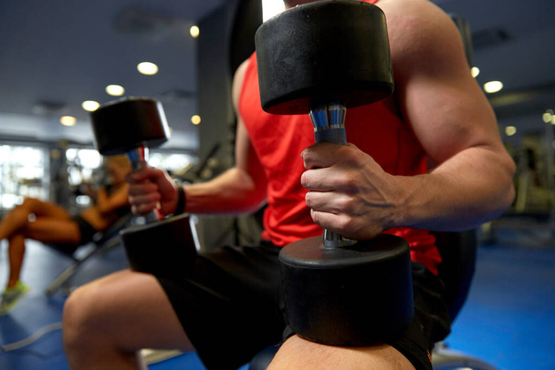 close up of man with dumbbells exercising in gym - Foto, Bild