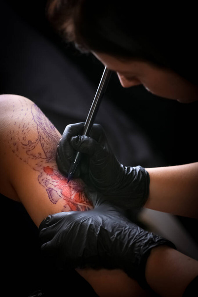 Female tattoo artist making tattoo on a men`s arm - Valokuva, kuva