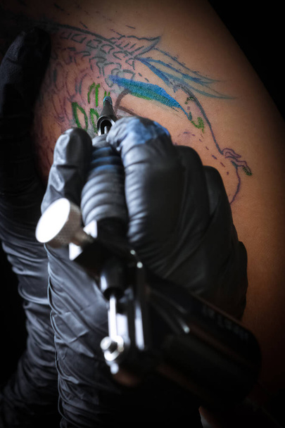 Tatuaje femenino artista haciendo tatuaje en el brazo de un hombre
 - Foto, Imagen