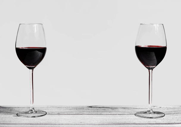 Twee glazen rode wijn op een donkere achtergrond met een ruimte in het midden om te schrijven - Foto, afbeelding