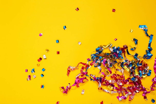 Colorful bright confetti and streamers on yellow background, top view. Copy space for text. Holiday mood, Christmas, New year, birthday or funny party. - Foto, immagini
