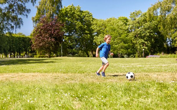 happy little boy with ball playing soccer at park - Φωτογραφία, εικόνα