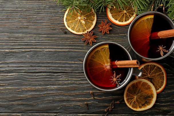 Cups with mulled wine, ingredients and pine branches on wooden background - Photo, Image