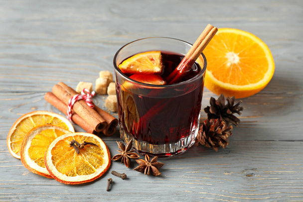 Glass of mulled wine and ingredients on gray wooden table - Фото, зображення
