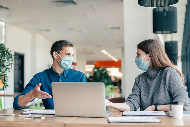 business colleagues in protective masks sitting at the office Desk. - Foto, Imagen