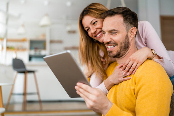 Couple in love hugging and using tablet together at home - Photo, Image