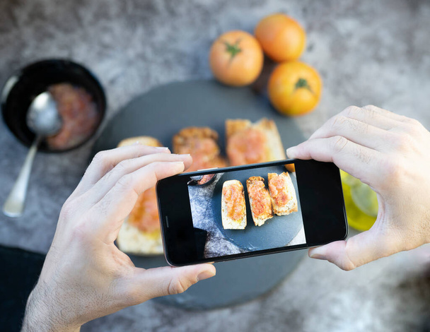 фотографирование хлеба с томатным и оливковым маслом, средиземноморский завтрак - Фото, изображение
