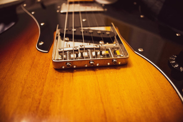 A closeup of the bridge of a sunburst electric guitar under the lights - 写真・画像