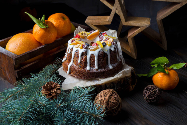 Χριστουγεννιάτικο cupcake με ζαχαρωμένα φρούτα σε ξύλινο τραπέζι σε φόντο από έλατα και πορτοκάλια. - Φωτογραφία, εικόνα