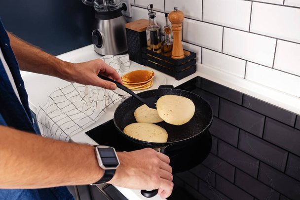 Man cooking pancakes for breakfast or brunch - Fotó, kép