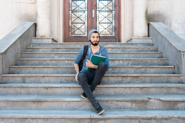 Μαθητής που κάθεται στην είσοδο του κολεγίου του περιμένοντας να ξεκινήσουν τα μαθήματα - Φωτογραφία, εικόνα