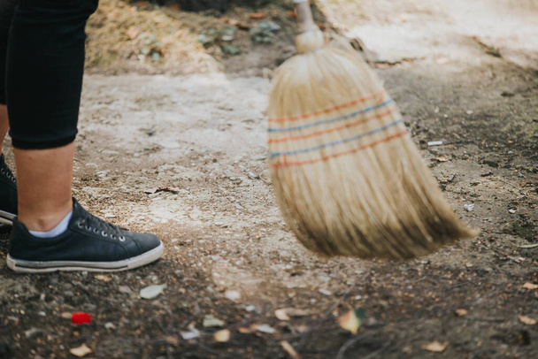 A closeup of a woman sweeping the street with a broom - Foto, immagini