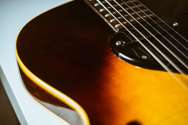 A closeup shot of a wooden guitar on the table - 写真・画像