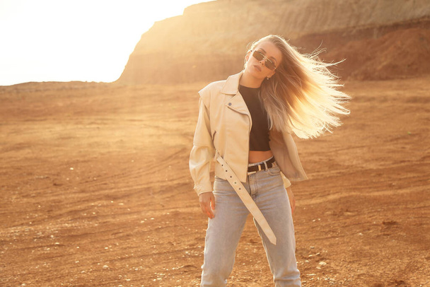 fashion outdoor photo of beautiful woman with blond hair in casual clothes posing in desert looking place - Foto, immagini