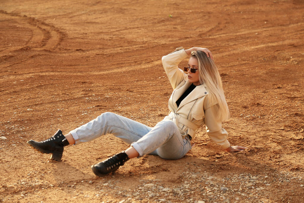 fashion outdoor photo of beautiful woman with blond hair in casual clothes posing in desert looking place - Photo, image