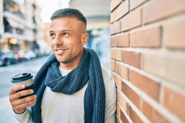 Fiatal fehér diák férfi mosolyog boldog ivás elvinni a kávét a városban. - Fotó, kép