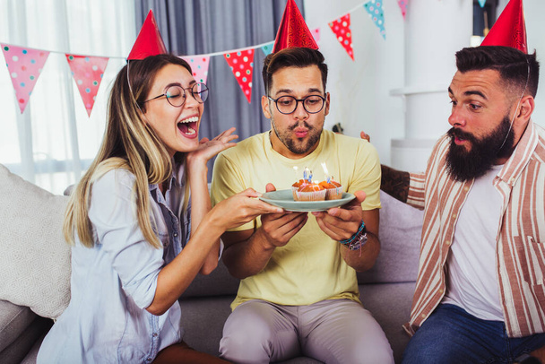 Группа счастливых людей, празднующих день рождения среди друзей и улыбающихся во время вечеринки - Фото, изображение