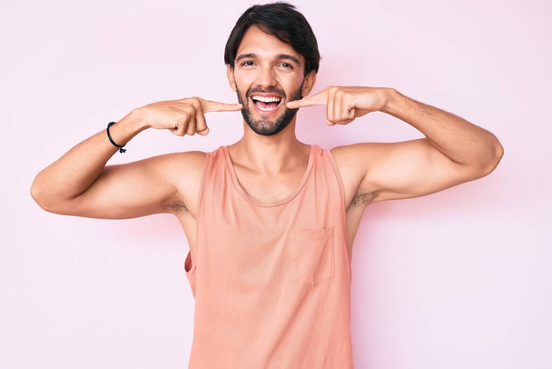 Handsome hispanic man wearing casual clothes smiling cheerful showing and pointing with fingers teeth and mouth. dental health concept.  - Φωτογραφία, εικόνα