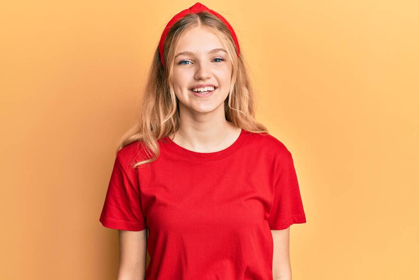 幸せとクールな笑顔でカジュアルな赤いTシャツを着た美しい若い白人の女の子。運のいい人.  - 写真・画像