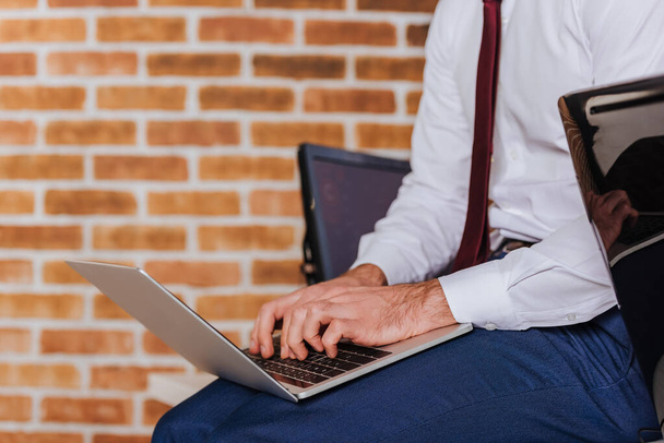 Rajatut näkymä liikemies kannettavan tietokoneen lähellä tietokoneen hämärtynyt etualalla  - Valokuva, kuva