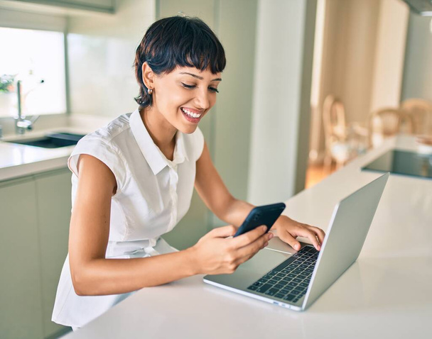 Schöne brünette Frau mit kurzen Haaren zu Hause mit Computer-Laptop - Foto, Bild