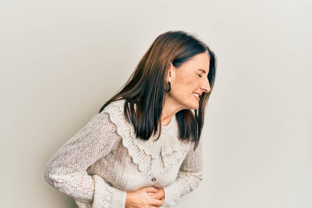 Middle age brunette woman wearing casual clothes with hand on stomach because nausea, painful disease feeling unwell. ache concept.  - Foto, imagen