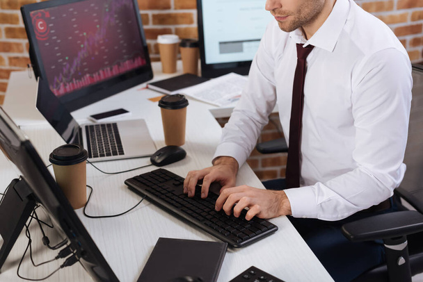 Vista recortada del hombre de negocios utilizando la computadora cerca de café y portátil en primer plano borrosa  - Foto, Imagen