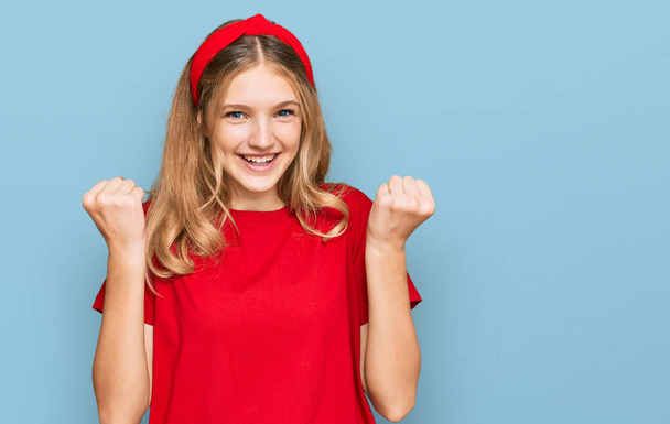 Belle jeune fille caucasienne portant T-shirt rouge occasionnel célébrant surpris et étonnés pour le succès avec les bras levés et les yeux ouverts. concept gagnant.  - Photo, image