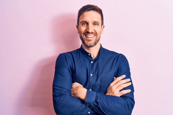 Young handsome man wearing casual shirt standing over isolated pink background happy face smiling with crossed arms looking at the camera. Positive person. - Φωτογραφία, εικόνα