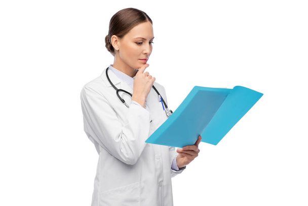 thinking female doctor with folder and stethoscope - Фото, изображение