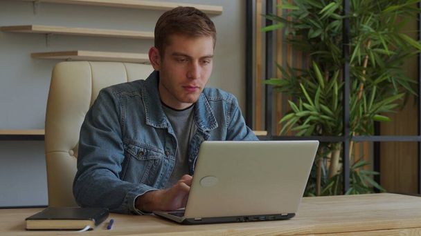Mosolygó ember dolgozik egy laptop, miközben ül az irodában - Fotó, kép