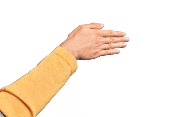 Mano de joven caucásico mostrando los dedos sobre fondo blanco aislado estirándose y alcanzando con la mano abierta para apretón de manos, mostrando la parte posterior de la mano - Foto, imagen