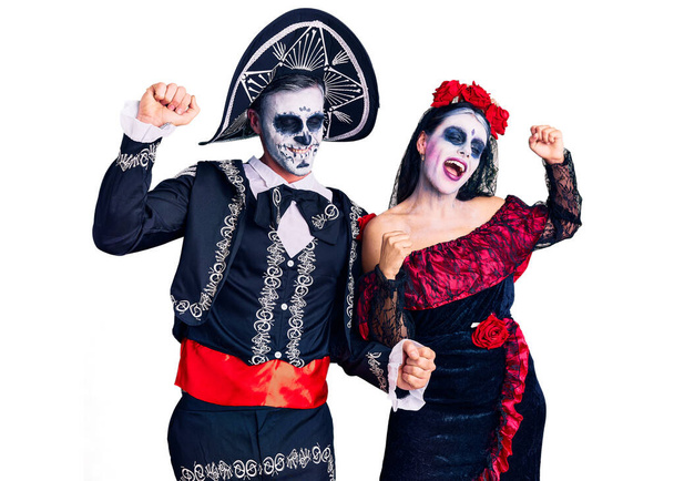 Νεαρό ζευγάρι φορώντας μεξικάνικη ημέρα του νεκρού κοστούμι πάνω από το υπόβαθρο χορεύουν χαρούμενα και χαρούμενα, χαμογελώντας κινείται casual και αυτοπεποίθηση ακούγοντας μουσική  - Φωτογραφία, εικόνα