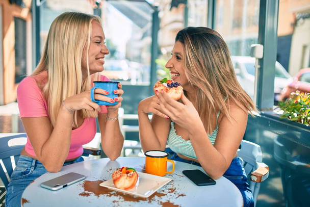 Két gyönyörű és fiatal lány barátok együtt szórakoznak cafeteria - Fotó, kép