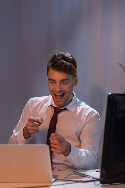 businessman pointing at laptop near computer on blurred foreground in office  - Photo, Image