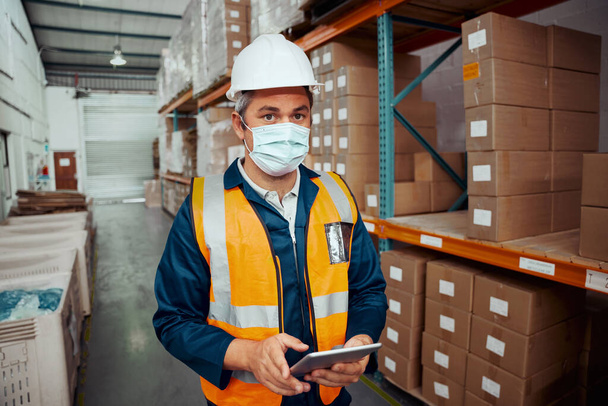 Portrait of a male supervisor in hardhat and protective vest holding digital tablet in warehouse - Zdjęcie, obraz