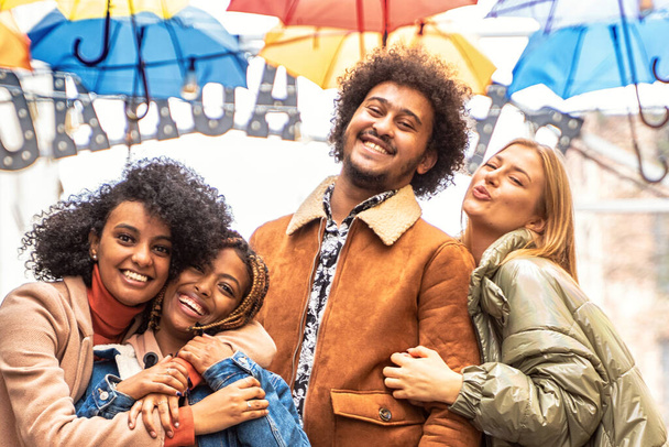 Group of multiracial friends having fun together outdoor in the city. Happy mixed race girls and boys smiling to the camera. Young people lifestyle concept. - Foto, Imagem