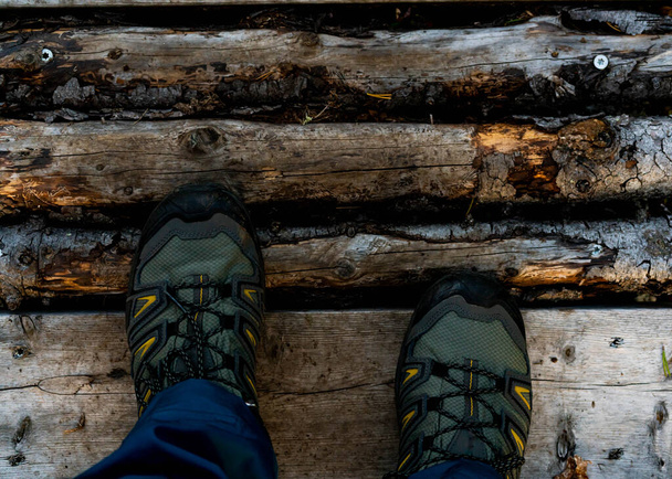 Botas de caminhantes em um trilho preenchido com troncos. Fecha. .. Foto de alta qualidade - Foto, Imagem