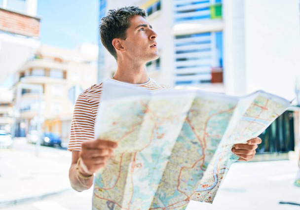 Fiatal jóképű kaukázusi turista férfi látszó város térképe az utcán - Fotó, kép