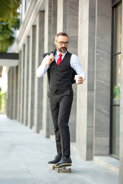 Brodaty hipsterski biznesmen trzymający portrety filiżanki kawy. - Zdjęcie, obraz