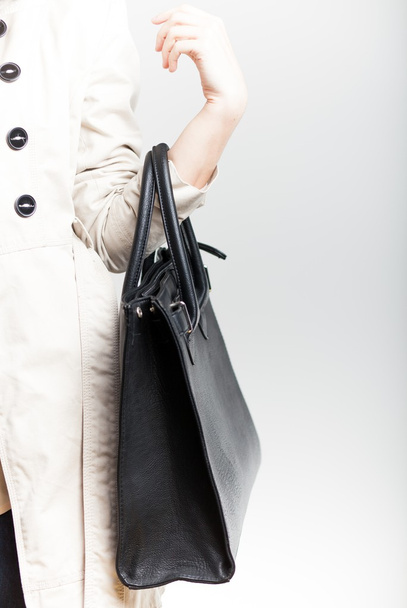 Elegant woman in coat with black leather bag - 写真・画像