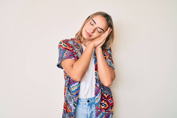 Young beautiful blonde woman wearing modern clothes sleeping tired dreaming and posing with hands together while smiling with closed eyes.  - Foto, Imagen