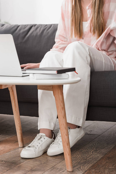 cropped view of freelancer sitting on couch and using laptop - Foto, Bild