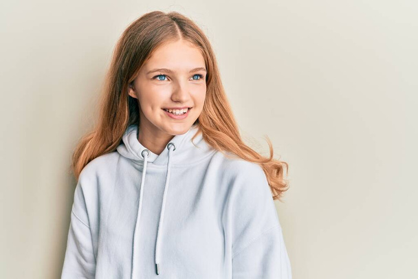 Beautiful young caucasian girl wearing casual sweatshirt looking to side, relax profile pose with natural face and confident smile.  - Photo, Image