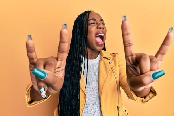 Young african american woman doing rock gesture angry and mad screaming frustrated and furious, shouting with anger looking up.  - Photo, Image